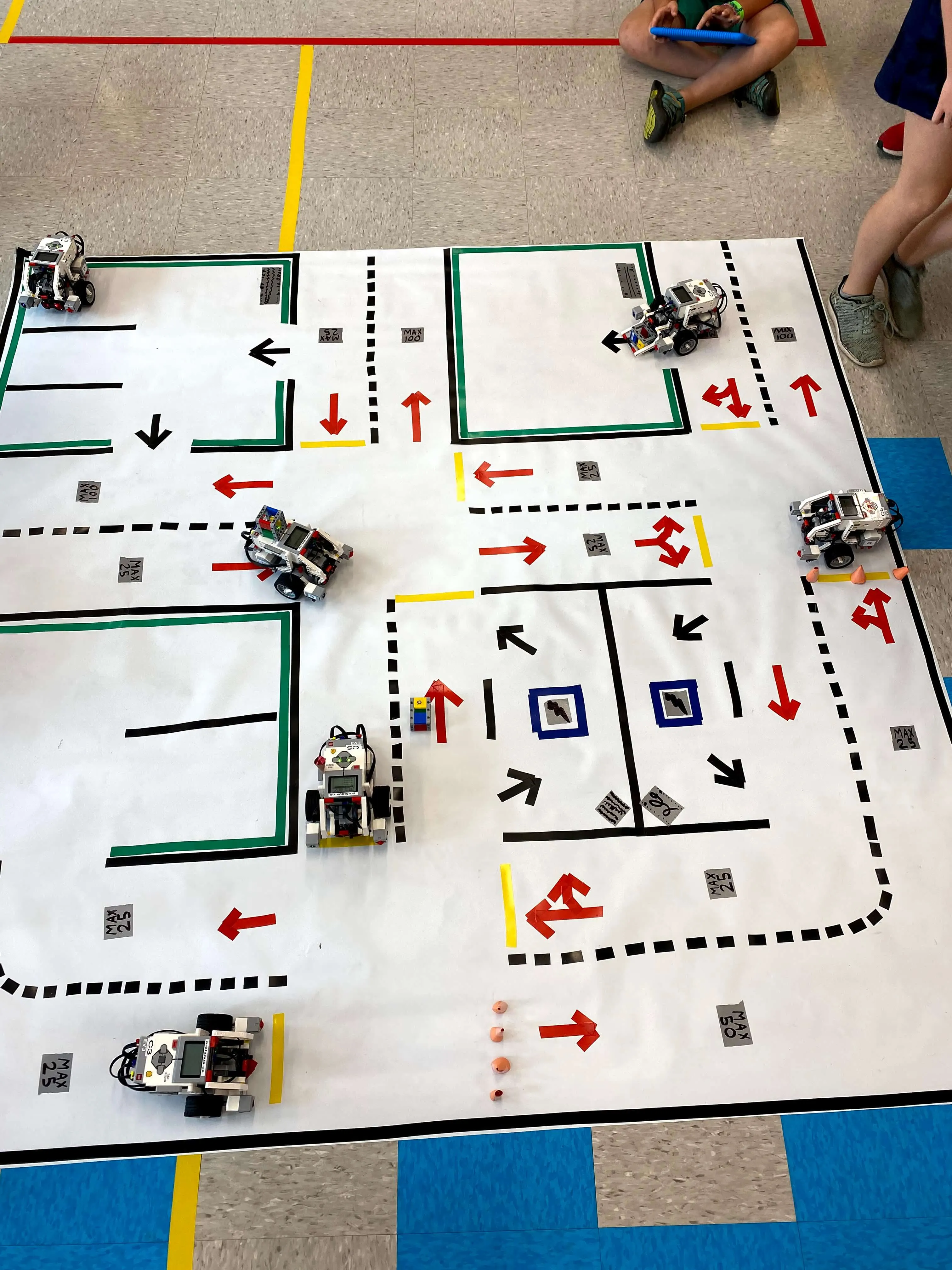 Des robots programmés circulent sur un tapis d’activité quadrillé avec des flèches