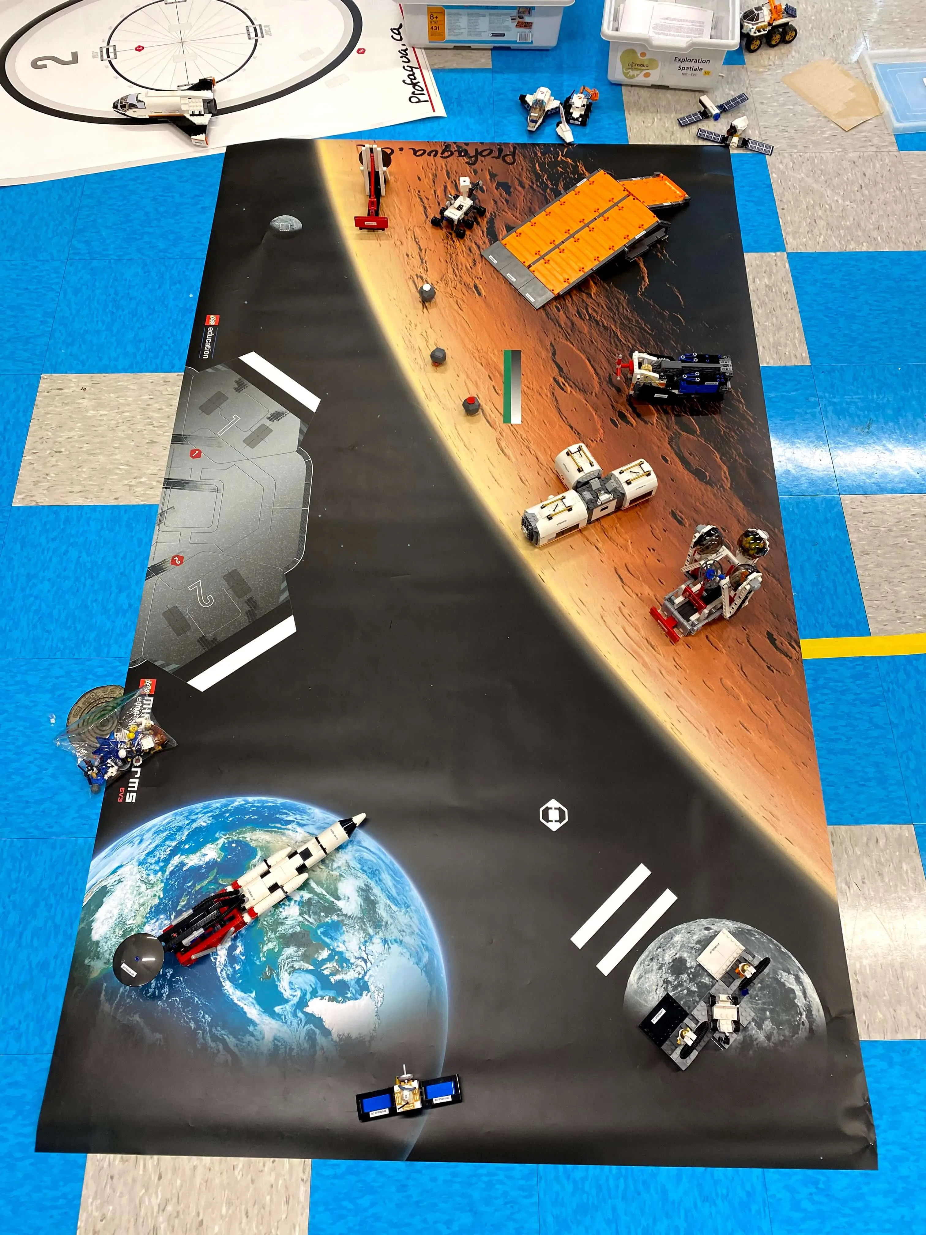 Des robots LEGO® en mission sur un tapis de l’espace avec la Terre, la Lune et Mars